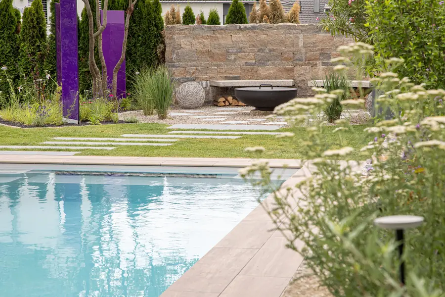 Pool mit angrenzender Natursteinmauer, Feuerschale und Holzlager